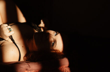 Femme allongée sur un lit, un regard perdu dans la lumière du matin.