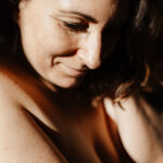 Photographie boudoir d’une femme, baignée par une lumière dorée et naturelle.