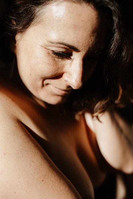 Photographie boudoir d’une femme, baignée par une lumière dorée et naturelle.