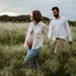 Future maman et papa marchant dans un champ de provence
